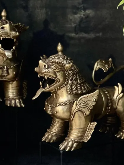 The pair of brass temple lions, shown from a slight angle. These guardians are handcrafted with incredible detail, from the bells around their necks to the wings on their sides.