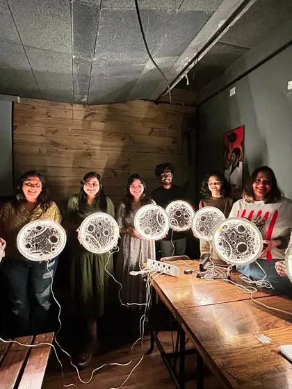 A fantastic group photo of participants proudly holding their finished moon lamps, all lit up and shining bright.
