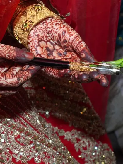 A detail shot from a Muslim wedding ceremony, showing the bride's hands with a pen and rose.