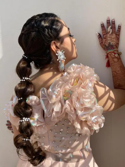 This side view shows how the pearl-accented balloon ponytail adds a fun and fashionable element to the bride's Mehendi look.