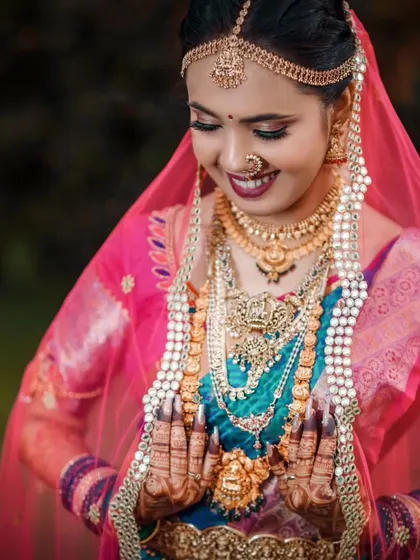 A close up portrait of a bride looking down, showcasing her intricate henna design and the delicate veil over her head.