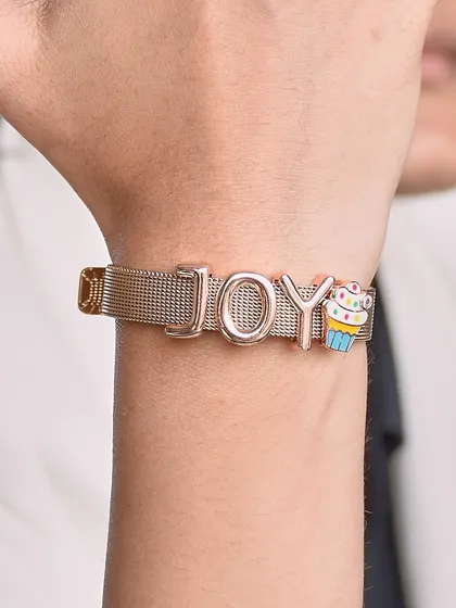 Find joy in the little things. This custom 'JOY' bracelet on a mesh band is paired with a colourful cupcake charm for a fun, happy vibe.