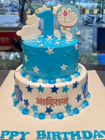 A starry, two-tier Doraemon cake for a first birthday celebration. This blue and white design is decorated with edible stars and a cute Doraemon topper.