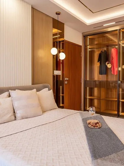 A view of the bedroom showcasing the spacious walk-in style wardrobe with smoked glass doors and internal lighting. The design combines luxury with practicality for easy organization.