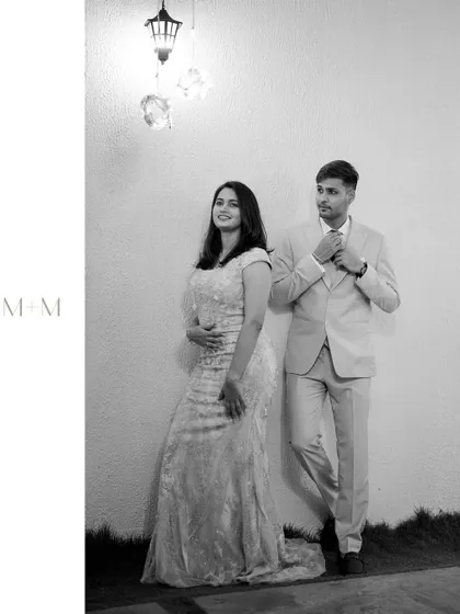 A classic black and white portrait of the couple posing against a simple wall, their elegant evening wear standing out.