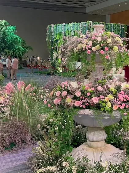 A beautiful fountain centerpiece overflowing with pink and white flowers, serving as a focal point in the enchanting garden setup.