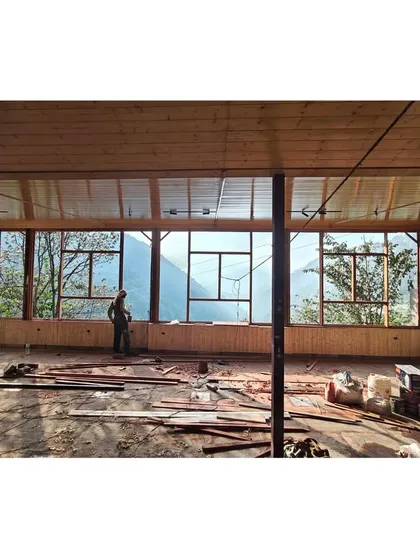 An in-progress view of the open pavilion. The design features a delicate butterfly roof that seems to float above the hills, creating a space that is sheltered yet completely open to the elements.