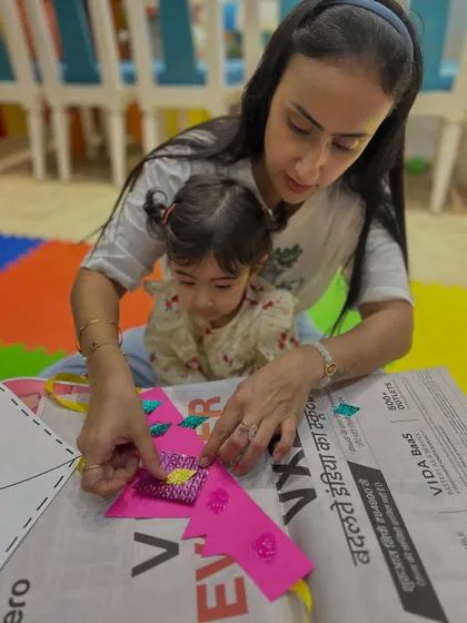 A mother and daughter work on a kite-making craft, a seasonal activity that connects learning to the world around them.