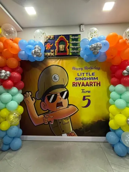 A Little Singham themed party setup with a custom character backdrop and colorful balloon pillars.