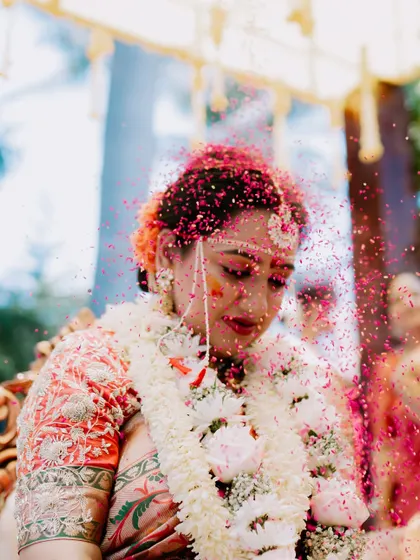 A vibrant shot of the bride being showered with colorful petals during a wedding ritual.