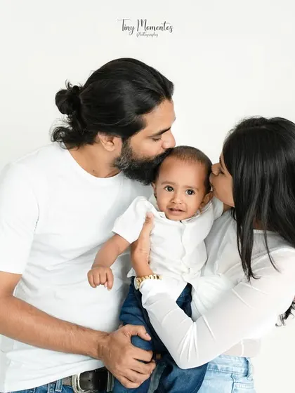Kisses from both mom and dad. This classic pose is all about surrounding the baby with love, and his sweet expression shows he feels it completely.