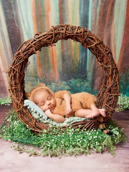 A sleepy little bear cub in the woods. This adorable setup features a newborn in a fuzzy bear costume, napping in a rustic nest.