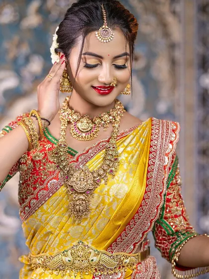 This bride looks so elegant in her yellow silk saree and temple jewellery. The set includes a Lakshmi choker, a matching haram, and a beautiful peacock Vaddanam.