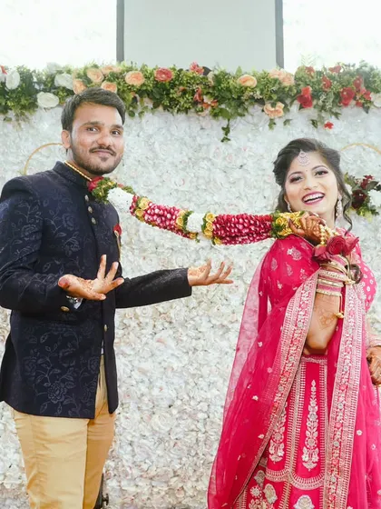 A playful moment between the happy couple. Her bright pink lehenga and his navy Jodhpuri suit make for a vibrant and joyful wedding day look.