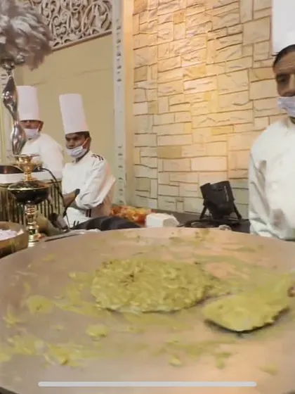 A chef preparing a dish on a large flat tawa at a live station. This method is perfect for a variety of vegetarian dishes and ensures the food is served piping hot.