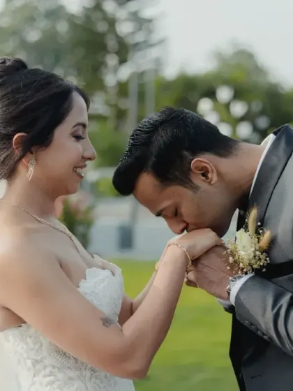 A groom gently kisses his bride's hand, a timeless gesture of love and respect, captured after their beautiful white wedding.