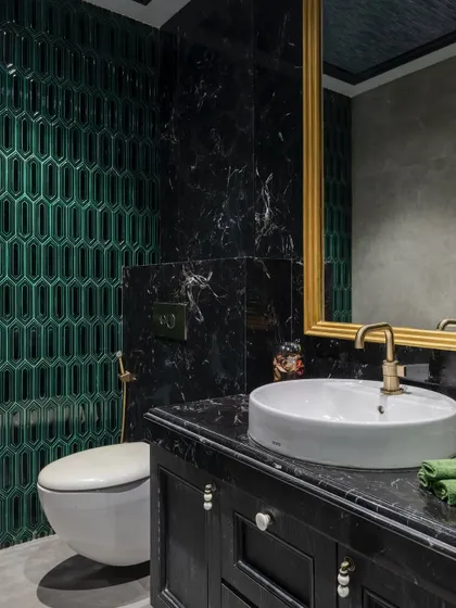 A close-up of the bathroom in 'The House of Arcs', showing the detail of the emerald green tiles and the black marble vanity.
