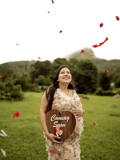 A joyful shot of the mom-to-be looking up as confetti falls around her, holding a "Coming Soon" sign. A perfect picture of celebration.