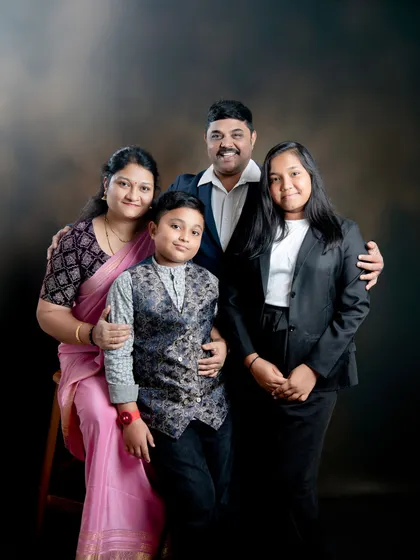 A formal family portrait against a classic dark, mottled backdrop. This style adds a sense of depth and timelessness to the photograph.