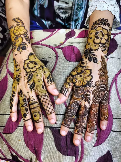 This design combines bold floral outlines with intricate fillers, shown here with the fresh organic henna paste.