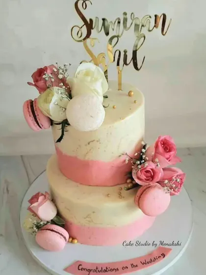 This two-tiered wedding cake is a beautiful example of my completely fondant-free work. It features a textured pink and white buttercream finish, adorned with fresh roses and delicate pink macarons for a touch of elegance.