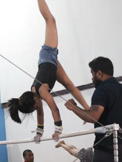 A coach provides hands-on support during uneven bar training. This is crucial for helping gymnasts learn advanced skills like handstands on the bar.