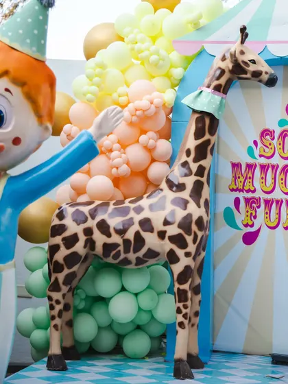 A close-up of the carnival animals, including a friendly giraffe and a happy clown, set against a backdrop of colorful balloons. These details bring the circus theme to life.