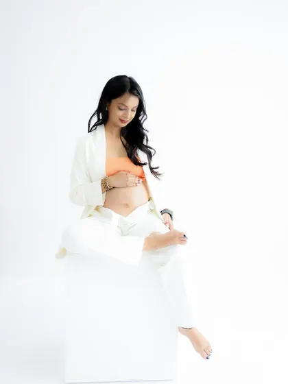 A modern and chic portrait. The mom-to-be's casual white and orange outfit is stylish and comfortable, perfect for a relaxed session.