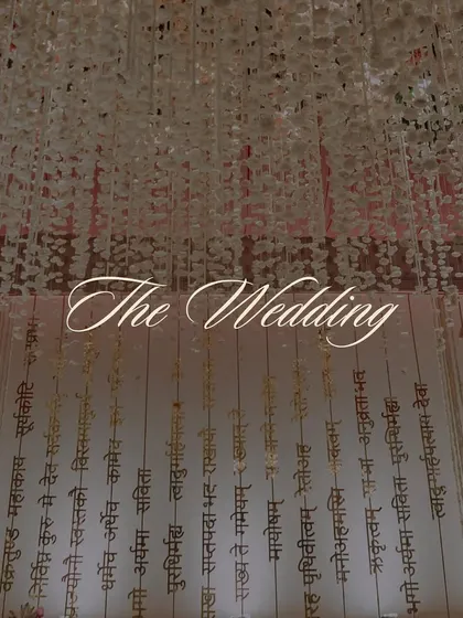 A title card for 'The Wedding', set against the backdrop of the hanging Sanskrit verses, emphasizing the traditional and sacred nature of the event.