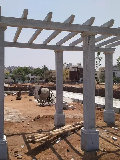 A large, multi-pillar stone pergola under construction. This will form a significant shaded area in a new public park or large garden.