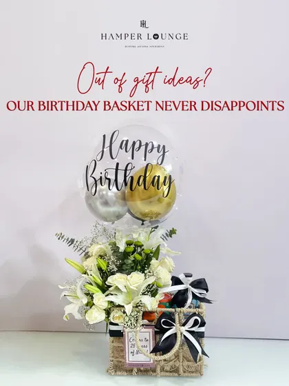 When you're out of gift ideas for him, a curated birthday basket is the perfect solution. This one combines a stylish jute basket with fresh white lilies, a "Happy Birthday" balloon, and a selection of his favorite essentials, tied with classic black and white ribbons.