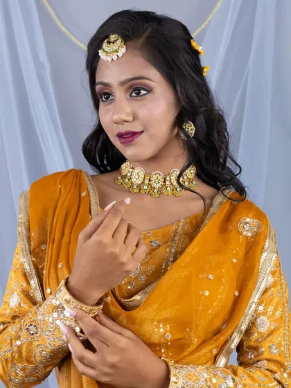 A close-up portrait showing the beautiful jewellery paired with the mustard lehenga, including a kundan choker and maang tikka.