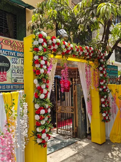 A bright and cheerful entrance gate for a daytime Haldi function. The yellow structure with red and white flowers is very welcoming.