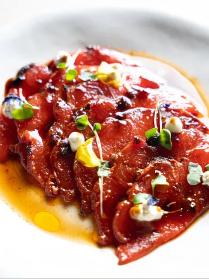 A delicate dish of sliced peppers with a light dressing and microgreens. This minimalist shot highlights our skill in capturing fine, artistic plating.