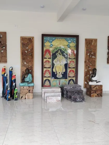 A display of various decorative items, including wooden parrot statues, a Buddha on a wooden block, and traditional Indian paintings.