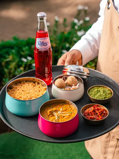 A server at Gallops presenting a tray of colorful Indian dishes. This classic service shot conveys a sense of hospitality and tradition.