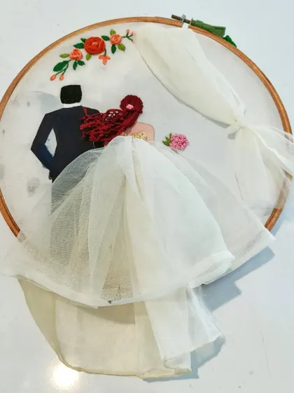 This hoop art captures a couple in Western wedding attire. The bride's veil and gown are crafted from delicate tulle fabric, adding a realistic and romantic touch.