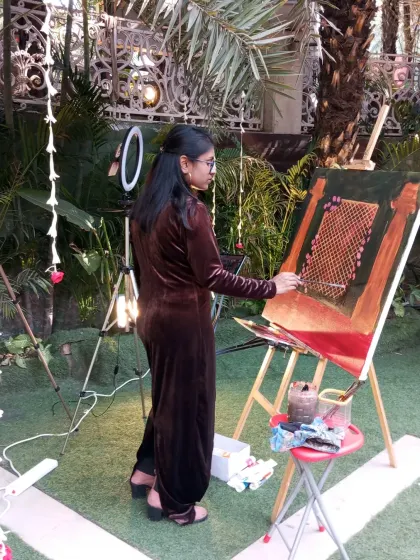 A shot of me painting live at Amaanta Farms. My setup is compact and professional, allowing me to work efficiently amidst the wedding festivities.