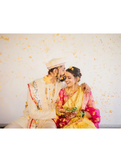 A beautiful moment of the groom kissing his bride's forehead under a shower of petals.