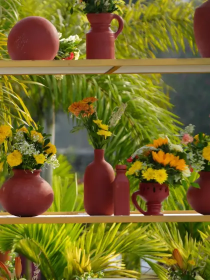 A detail shot of terracotta pots filled with colorful flowers, displayed on a modern shelving unit.