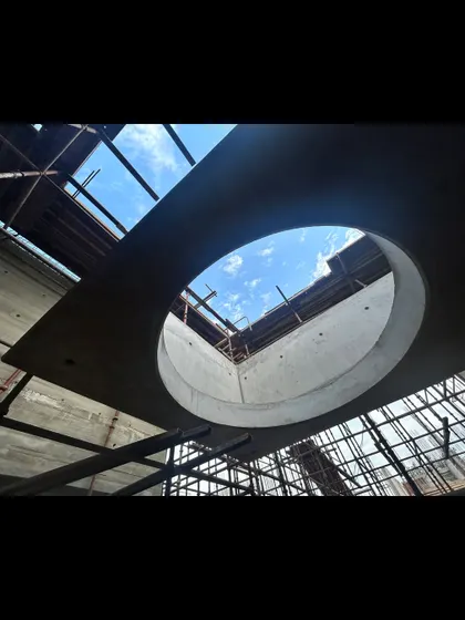 Looking up through a large circular oculus in the concrete roof slab of the Moradabad project. This element is designed to bring a dramatic column of light down into the interior space.