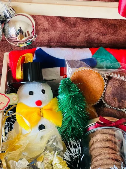 A close-up of the Christmas hamper's contents, showing the snowman, cupcakes, and cookies in detail.