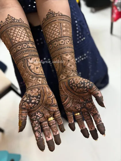 A complete view of the asymmetrical bridal mehendi, showing both hands together. This style allows the bride to have two distinct yet complementary designs.