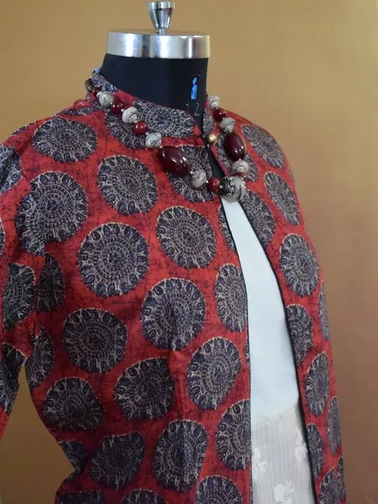 An angled view of the red and black printed jacket, highlighting the mandarin collar and the rich texture of the poly-silk fabric.