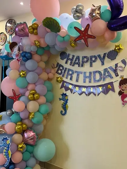 A wider view of the mermaid balloon arch, showing its placement in a home setting.