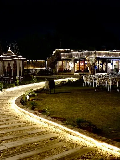 A view of my venue at night, showcasing the different spaces available. From the lit pathways and lush lawns to the private cabanas and indoor hall, you can see how it all comes together to create a special ambiance.