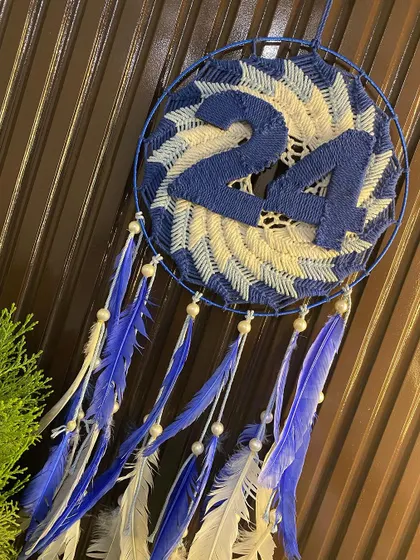 Another view of the lucky number 24 dreamcatcher, this time styled next to a small plant, showing how it can be incorporated into your home decor.