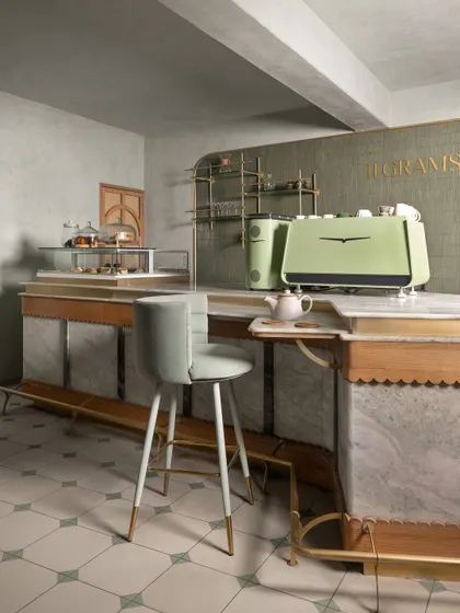 The bar at 11 Grams features a stunning marble-clad front with scalloped wood trim and brass details. The custom-designed bar stool has a soft, modern silhouette that contrasts beautifully with the classic materials.