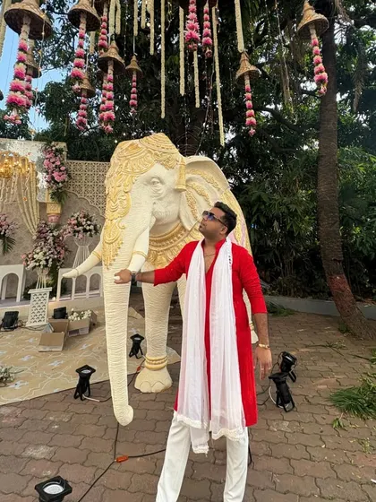 A wider shot of the red kurta outfit, showing how it stands out against the grand wedding decor.