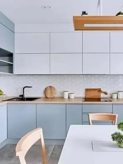 A Scandinavian-style L-shaped kitchen with light blue and white cabinets. The integrated appliances and light wood accents complete the clean and minimalist aesthetic.